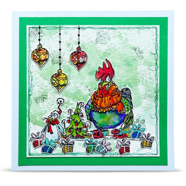 A square Christmas greeting card featuring a whimsical illustration of a rooster wearing an orange scarf, surrounded by ornaments, a decorated tree, and wrapped gifts. The card has a white border, a green inner border, and a vibrant green outer border.
