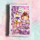 A square mixed-media art card featuring a whimsical illustration of a girl painting at an easel, surrounded by purple and pink abstract textures, with the words 'Paint happy' on a torn paper label. The card has a scalloped white border and is photographed against a pastel pink and mint watercolor background.