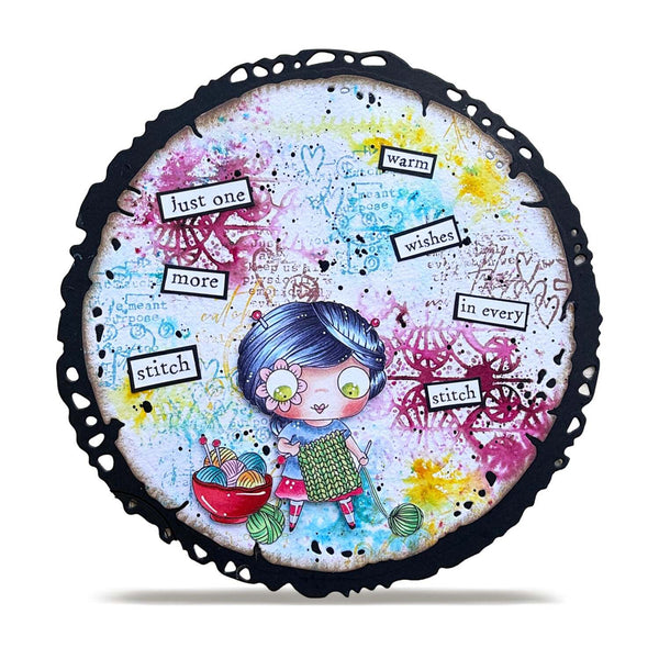 A round decorative plaque or coaster with a scalloped black edge, featuring a colorful whimsical illustration of a girl with blue hair surrounded by paint splatters, small text labels, and yarn balls on a white background.