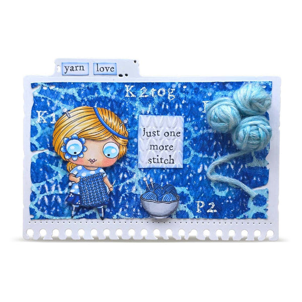 A square handmade art card or scrapbook page featuring a blue abstract textured background with a cartoon girl holding knitting needles, yarn balls, and text including 'yarn love', 'Ktog', 'Just one more stitch', and 'P2'.