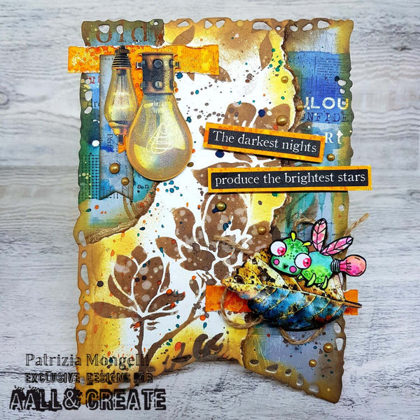 A handmade mixed-media art card featuring distressed brown and gold paper textures, two vintage lightbulb embellishments, a green cartoon frog with pink wings, and text stickers reading 'The darkest nights produce the brightest stars'.