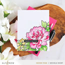 Floral card with pink flower design on a wooden surface with flowers and a pen.