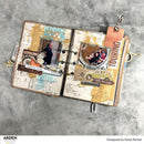 Open scrapbook with travel-themed pages on a gray surface, featuring images of people and vehicles.