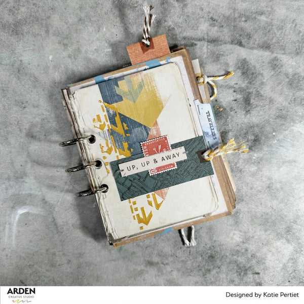 Small notebook with decorative cover on a textured gray surface, featuring the brand 'Arden Creative Studio'.