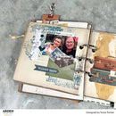 Open scrapbook with travel-themed pages on a textured surface, featuring text and images of people and travel items.