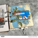 Open notebook with decorative pages featuring nature and travel-themed illustrations on a gray surface.