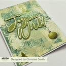 A handmade greeting card featuring the raised die-cut text 'Joy to the World' in olive green over a textured cream and green background, with a small ornament detail. The card is photographed on a white surface, with an ARDEN Creative Studios label and 'Designed by Christine Smith' text visible at the bottom.