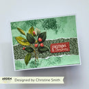 A handmade greeting card with a green textured background, a central dark green patterned band, a leafy green and gold branch with red berries, and a red label that reads 'COUNTDOWN to Christmas.' The card is photographed on a light gray background with a banner below reading 'Designed by Christine Smith' and 'ARDEN' branding.