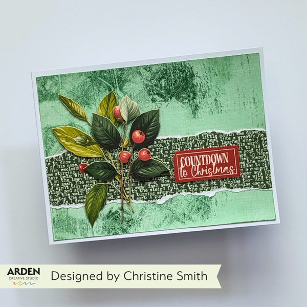 A handmade greeting card with a green textured background, a central dark green patterned band, a leafy green and gold branch with red berries, and a red label that reads 'COUNTDOWN to Christmas.' The card is photographed on a light gray background with a banner below reading 'Designed by Christine Smith' and 'ARDEN' branding.