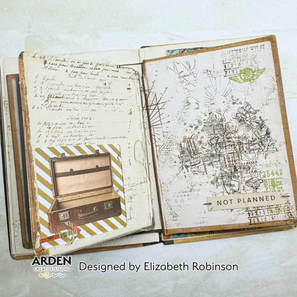 An open handmade paper journal or notebook spread, showing two decorated pages with handwritten notes, stamps, collage elements, and a suitcase illustration. The pages are photographed on a light neutral background with branding text at the bottom reading 'ARDEN' and 'Designed by Elizabeth Robinson'.