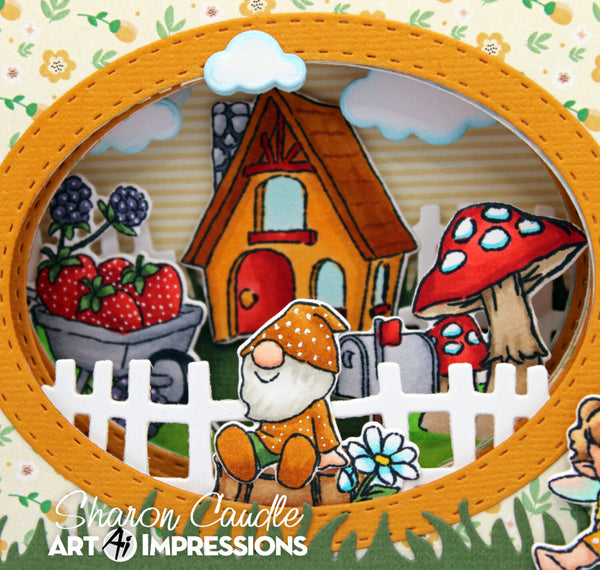A handmade layered shadow box craft featuring a whimsical garden scene with a gnome, strawberry patch, red-capped mushroom, small house, fence, and clouds, framed in orange faux leather. The text 'Sharon Caudle Art 41 Impressions' is visible at the bottom.