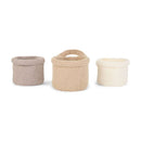 Three small woven storage baskets with lids in neutral tones, shown on a plain white background. The left basket is a light taupe-beige, the center basket is a natural straw beige with a top handle, and the right basket is off-white/cream.