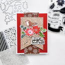 A handmade Christmas greeting card with layered red, brown, and beige paper elements, a bird illustration, poinsettias, holly leaves, and the phrase 'Have a joyful holiday season.' The card is photographed on a white surface with craft dies and clear stamps visible around it.