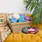 Basket of colorful yarn on a mustard yellow couch with a plant in the background