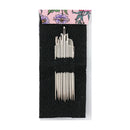 A set of white sewing pins arranged in two groups on a black mesh display card, with a pink floral header card at the top, photographed against a plain white background.