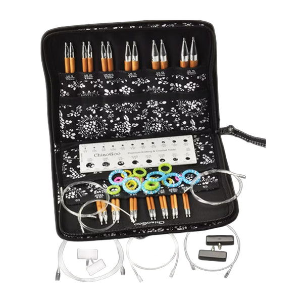 An open black zippered knitting needle kit case on a white background, containing multiple knitting needles, a metal size gauge, colorful stitch markers, and cable ties.