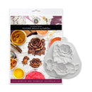 A silicone mould for sculpted roses by Kate Sue, shown alongside its retail packaging. The packaging features a collage of colorful clay and resin works, and the white silicone mould itself is displayed to the right, showing the detailed rose and leaf cavity shapes.