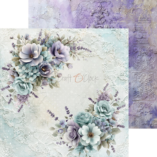 A decorative scrapbook paper sheet with floral corner arrangements in soft lavender, blue, and white, layered over a textured vintage-style background. A second matching patterned sheet is partially visible behind it.