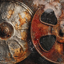Close-up of two rusted metal film reels or spools with peeling paint, showing textured brown, orange, and gray surfaces with dark openings.