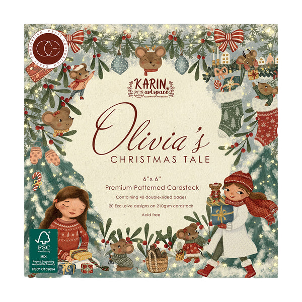 Karin Cardstock 'Olivia's Christmas Tale' 6x6 inch cardstock box featuring festive illustrated designs with Christmas trees, mice, children, ornaments, and holiday decorations on a cream background.