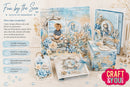 A collection of handmade paper crafting products themed around 'Fun by the Sea - Ocean of Memories', including an album, cards, a box, and a hanging tag, decorated with blue and beige nautical illustrations. The products are arranged on a light beige surface with a matching background, featuring a 'Craft & You' brand logo in the bottom right corner.