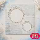 A square craft template or stencil sheet featuring two rope-wrapped circular cutouts, displayed on a light blue distressed wood background with decorative seashells and pearls. A pink 'CRAFT & YOU DESIGN' logo is visible in the bottom right corner.