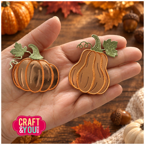 Two autumn-themed metal cutters shaped like pumpkins with green leaves and stems, held in a person's hand over a rustic fall-themed background with leaves, acorns, and small pumpkins. A pink 'CRAFT & YOU' logo is visible in the lower-left corner.