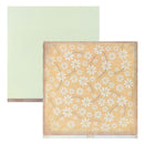 A sheet of floral patterned cardstock with light mint daisy-like flowers on a pale peach background, shown in front of a plain sage green cardstock sheet. 
