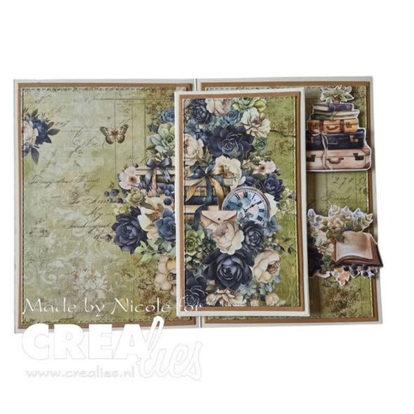 A vintage-style scrapbook or card-making kit shown open, featuring layered floral panels with blue and cream roses, script paper, a butterfly, a clock, stacked suitcases, and an open book. The product is photographed on a plain white background with a visible 'Made by Nicole For CreaLies' watermark across the lower left.