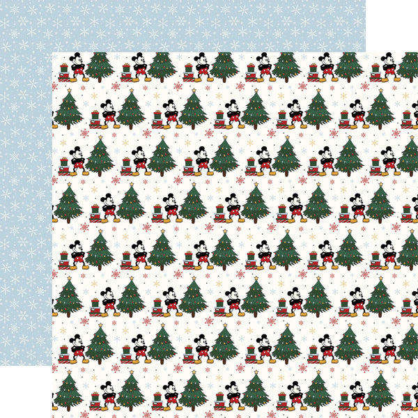 A sheet of double-sided scrapbooking paper with a Christmas Mickey Mouse pattern. The front features a repeating pattern of Mickey Mouse wearing red sweaters and scarves next to green Christmas trees with gifts, on a cream background with small pink snowflakes.