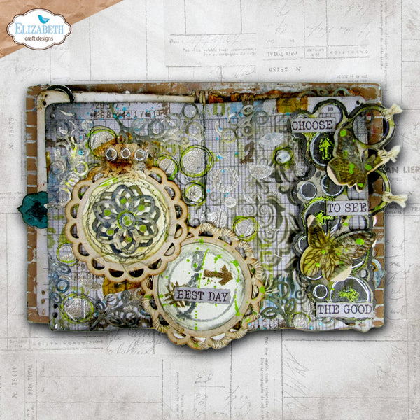 A square mixed-media collage or scrapbook page featuring vintage-style embellishments, layered paper circles, a butterfly cutout, text phrases like 'BEST DAY' and 'TO SEE THE GOOD', and a distressed brown border, shown on a light textured paper background. The Elizabeth craft designs logo appears in the top-left corner.