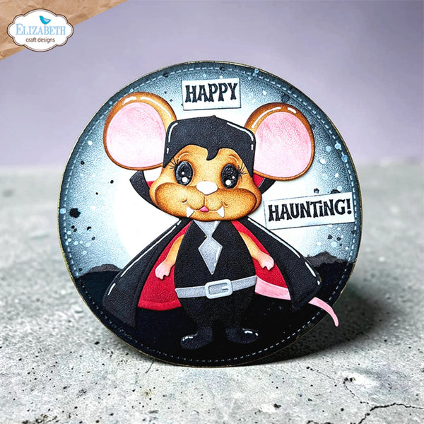 A round craft die-cut sticker or decal featuring a cartoon vampire mouse wearing a black cape and suit with pink inner ears, set against a dark starry background with the words 'HAPPY HAUNTING!'. The brand logo 'Elizabeth craft designs' is visible in the top-left corner.