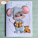 A handmade greeting card featuring a cute cartoon mouse wearing a striped nightcap and pajamas while reading a book, with a small teddy bear at its side. The card is displayed on a green patterned fabric background.