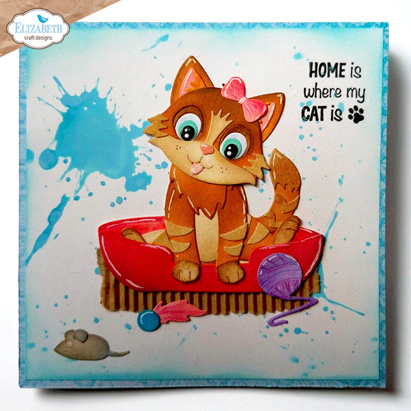 A square decorative sign or canvas featuring a cartoon orange tabby cat sitting in a red boat on a striped base, with blue paint splatter graphics, a small gray mouse, a purple ball of yarn, and the text 'HOME is where my CAT is' with a paw print. The sign has a blue border and is photographed against a white background.