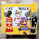 A handmade craft scrapbook card featuring three cute cartoon cats in different outfits under the text 'CAT WALK'. The card has a yellow star-patterned border, a white center, and is displayed on a neutral textured surface.