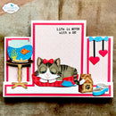 A handmade pop-up card featuring a sleeping tabby and white cat with a red bow, surrounded by pop-up elements including a fishbowl, cat food bowl, and hearts. The card has pink and white stripes and the text 'Life is BETTER with a CAT'.