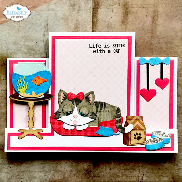 A handmade pop-up card featuring a sleeping tabby and white cat with a red bow, surrounded by pop-up elements including a fishbowl, cat food bowl, and hearts. The card has pink and white stripes and the text 'Life is BETTER with a CAT'.