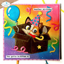 A handmade birthday card featuring a cartoon kitten peeking out of a box with a party hat and a party horn. The card has a colorful rainbow gradient background with confetti and streamers, and text reading 'Another birthday?' and 'You gotta be kitten me!'.