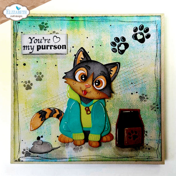 A square handmade greeting card featuring a cute cartoon cat in a teal hoodie with the text 'You're my purrson'. The card has a textured, watercolor-like background in shades of green, yellow, and blue, decorated with black paw prints, a small mouse, and a brown cat food bowl.