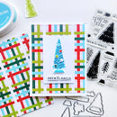 A handmade Christmas card with a blue tree design and 'DECK THE HALLS' text, styled with patterned paper, clear stamps, and metal dies on a white background.