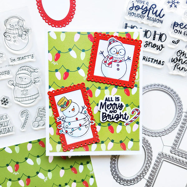 A festive handmade holiday card set displayed on a white background with coordinating clear stamps and metal die templates. The main card features a green Christmas lights pattern with two red scalloped frames containing snowman illustrations and the phrase 'ALL IS Merry and Bright?'.