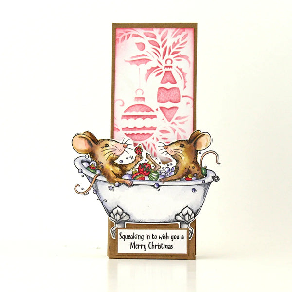A handmade Christmas greeting card featuring two mice sitting in a bathtub filled with ornaments and candy, with a pink and brown festive background panel and a message box that reads 'Squeaking in to wish you a Merry Christmas'.