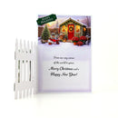 A Christmas greeting card with a white picket fence on the left side, showing a snowy holiday scene with a decorated cabin, Christmas tree, and red sleigh. The card includes the text 'Happy Holidays' and 'Merry Christmas and a Happy New Year!'.