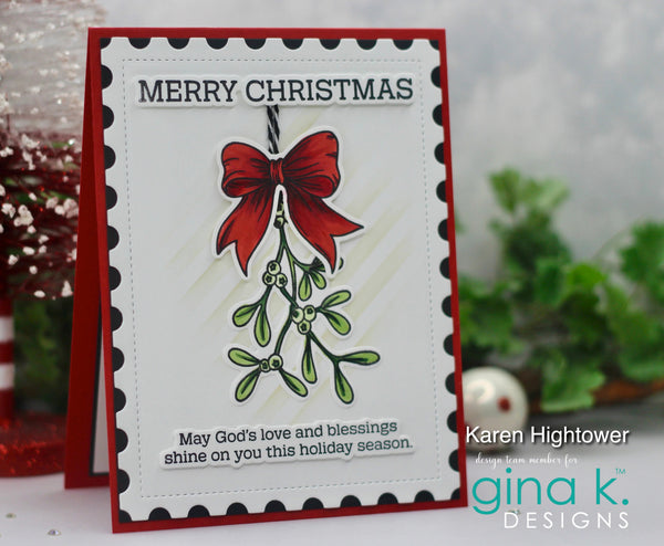 A handmade Christmas greeting card with a red border, black scalloped inner border, and a central mistletoe illustration with a red bow. The card reads “MERRY CHRISTMAS” at the top and “May God’s love and blessings shine on you this holiday season.