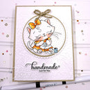 A handmade greeting card featuring a cute white cat illustration in an orange dress and bow, sitting on a scalloped circular background. The card has the words 'handmade Just for You' printed on it and is styled with a white pen in the foreground on a light pink background with scattered rhinestones.