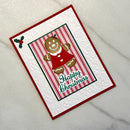 A handmade Christmas greeting card featuring a gingerbread man in a red dress, a red and green striped central panel, and the words 'Happy Christmas' in green script. The card has a red border and a white embossed background with subtle floral and snowflake patterns, photographed on a light textured surface.