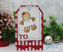 A handmade Christmas greeting card tag featuring a gingerbread man figure in a white dress with red polka dots, set against a red and white patterned border. The tag is decorated with the word 'TO' in red and is shown with holiday decorations in the background.