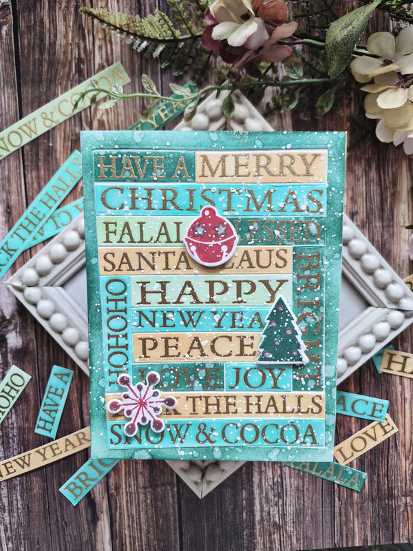 A handmade Christmas greeting card with a turquoise background and layered wooden-textured strips featuring holiday phrases like 'Have a Merry Christmas' and 'HAPPY NEW YEAR'. The card is styled on a rustic wooden surface with scattered matching paper strips, white beads, and dried flowers.