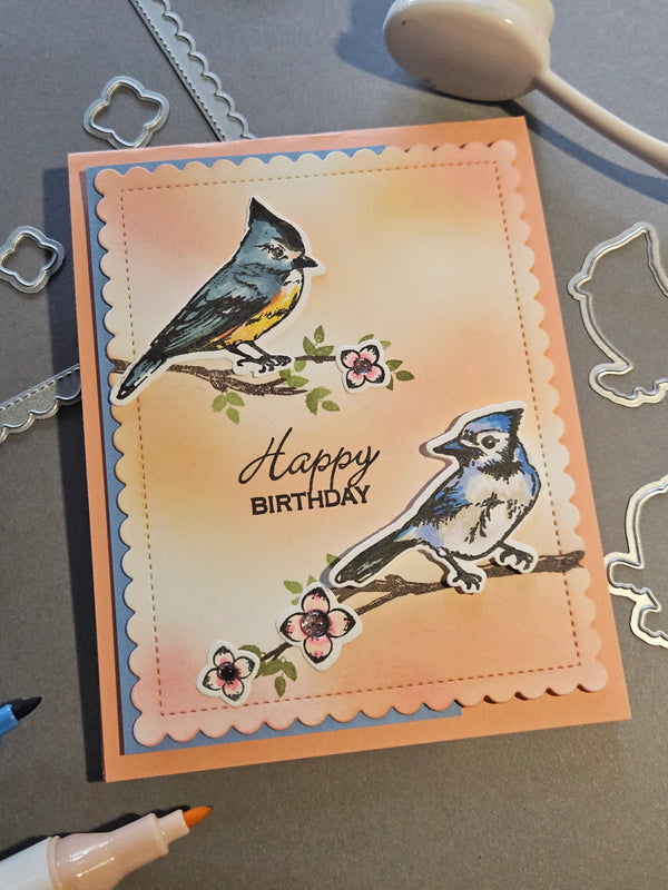 Handmade birthday card with bird illustrations on a gray surface