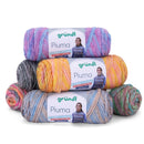 Four skeins of Grundl Piuma yarn stacked in a pyramid on a white background. The yarns are variegated with multiple colors including pink, purple, blue, yellow, orange, and gray, and each skein has its own paper label with the 'grundl Piuma' branding.